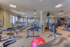 Ein Fitnessraum mit Laufbändern, Crosstrainern und Gewichten.
