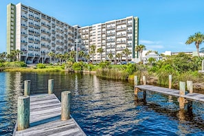 A multi-story hotel with balconies, a dock, and a water body in front. - Beautiful beachfront condo with shared pool and beach access (Panama City Beach)