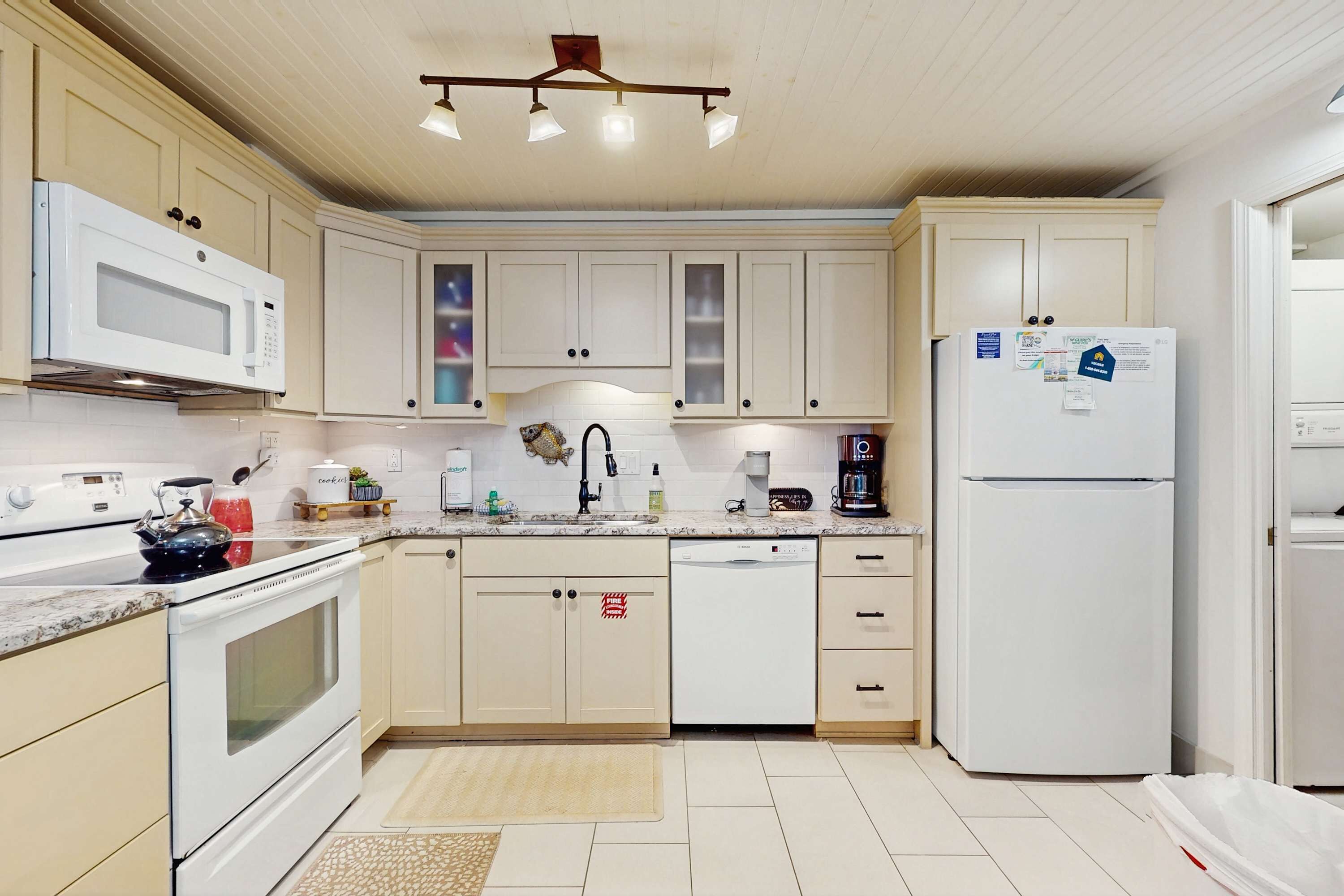 A kitchen with white cabinets, a microwave, a dishwasher, and a refrigerator.