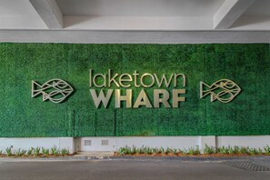 A sign for Laketown WHARF with a green wall background and decorative fish motifs. - Serene condo with pool, washer/dryer, kitchen, & hot tub - snowbird friendly (Panama City Beach)
