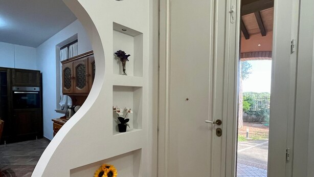 Um interior moderno com uma parede curva branca, uma porta e um chão ladrilhado.