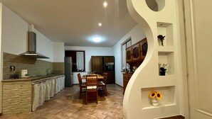 Cozinha moderna com área de refeições, destacando uma ilha grande, armários de madeira e um design de parede branca exclusivo.