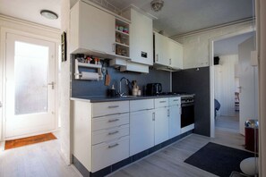 Eine moderne Küche mit weißen Schränken, einer schwarzen Arbeitsplatte und einem eingebauten Backofen.