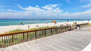 A wooden boardwalk leading to a sandy beach with a clear blue sky. - Beachfront Condo, gorgeous views, shared pool and beach access (Panama City Beach)