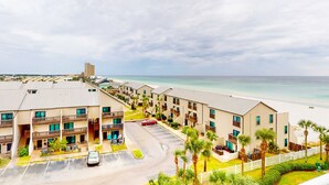A beachfront hotel with multiple-story buildings, a parking lot, and a view of the ocean. - Beachfront Condo, gorgeous views, shared pool and beach access (Panama City Beach)
