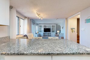 Una cocina moderna con encimeras de granito, televisor integrado y comedor con mesa y sillas.
