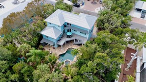 A large two-story house with a swimming pool, surrounded by dense tropical vegetation. - Mangrove Mojito - Amazing Outdoor Space! (Anna Maria)