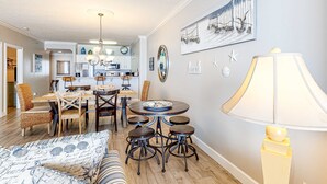 A dining area with a round table, four stools, and a chandelier. - Stunning beachfront condo with water views, pool, hot tub, & sauna (Panama City Beach)