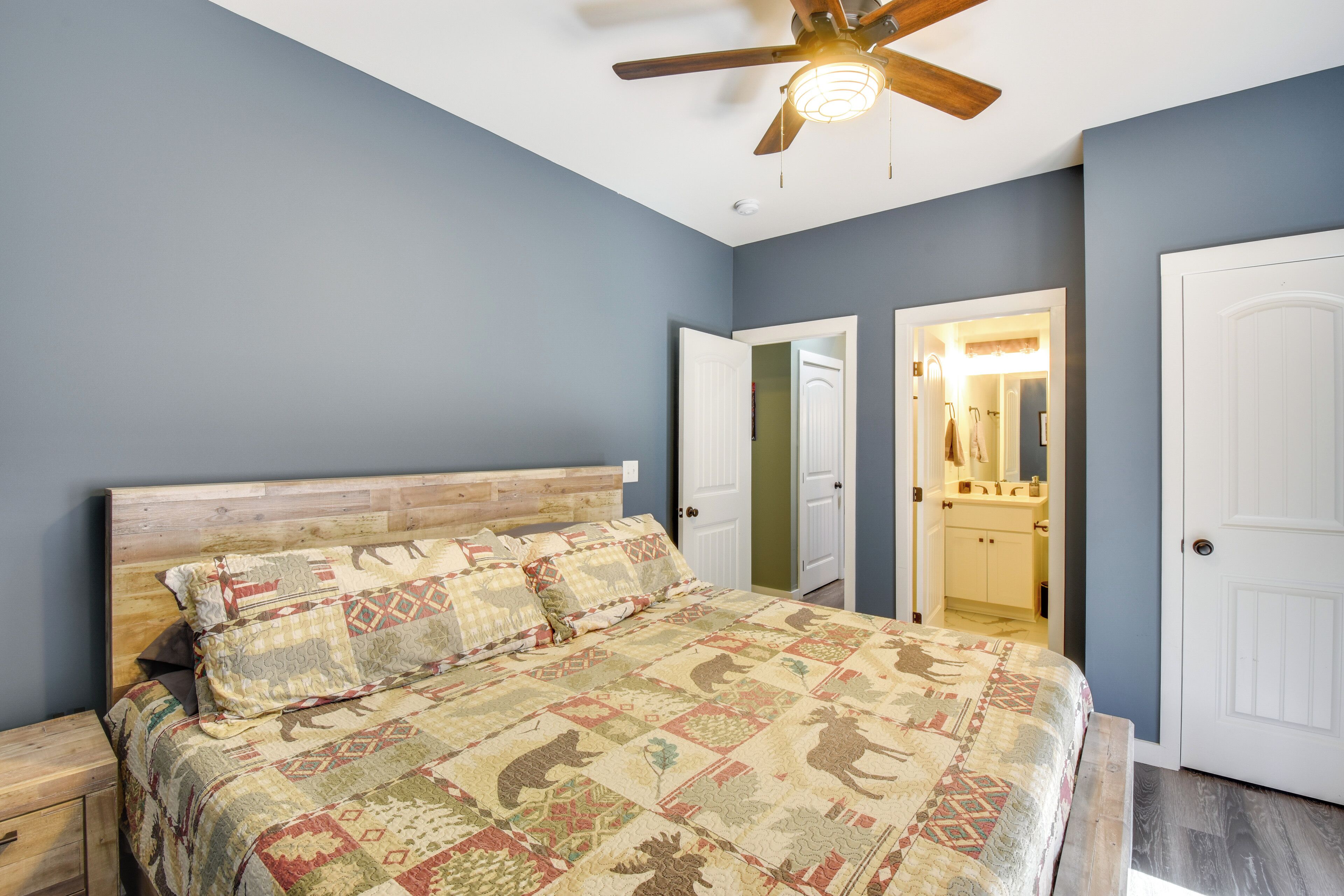 A bedroom with a wooden headboard, a quilted bedspread, and a ceiling fan.