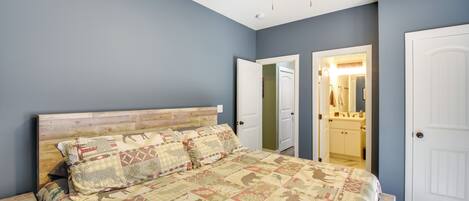 A bedroom with a wooden headboard, a quilted bedspread, and a ceiling fan.