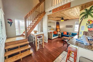 Un amplio espacio habitable con una escalera de madera, una cocina y un comedor.