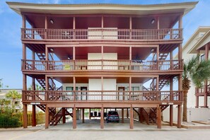 A multi-story building with balconies and a car parked in front.