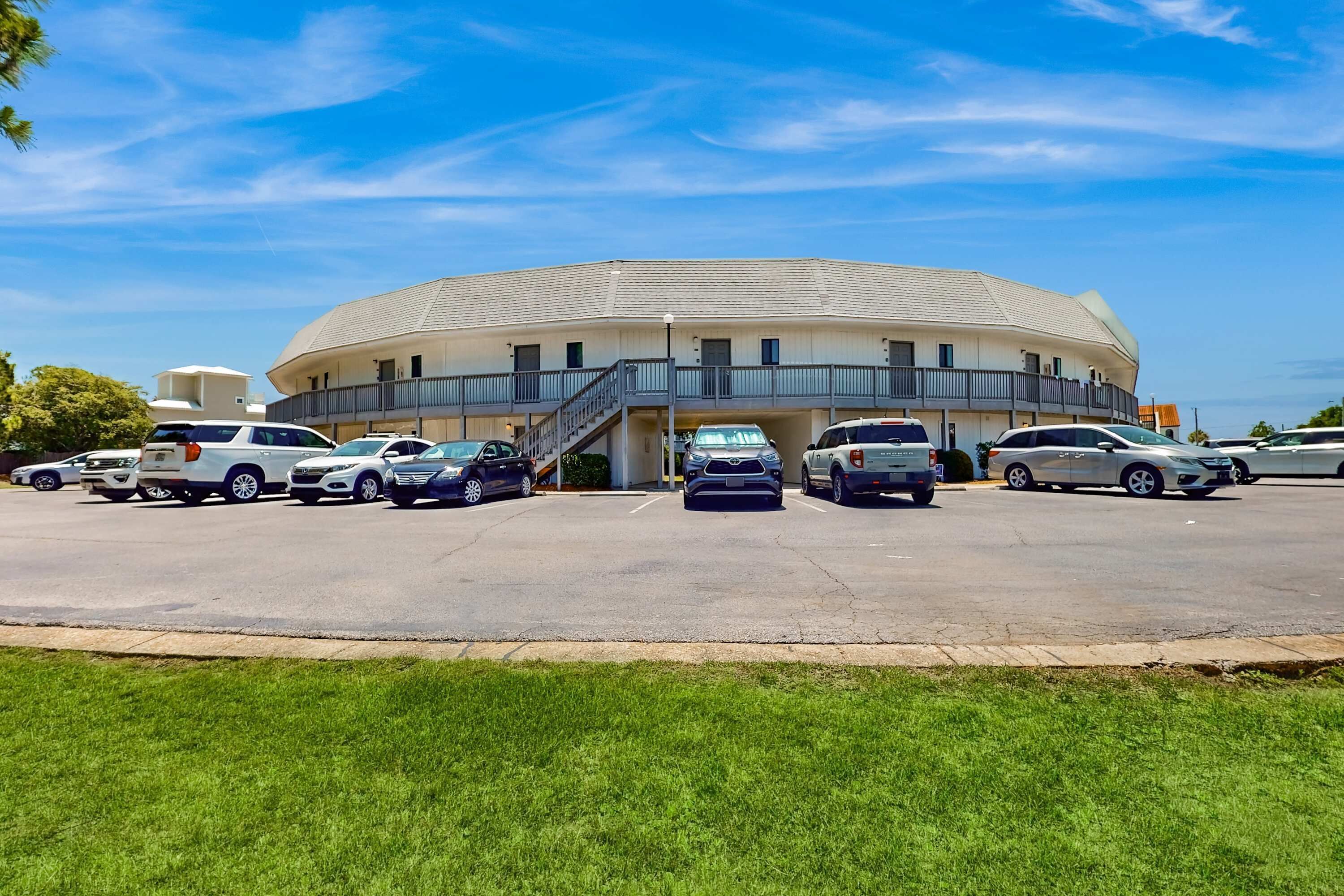 A multi-story hotel with a curved roof and a parking lot in front.