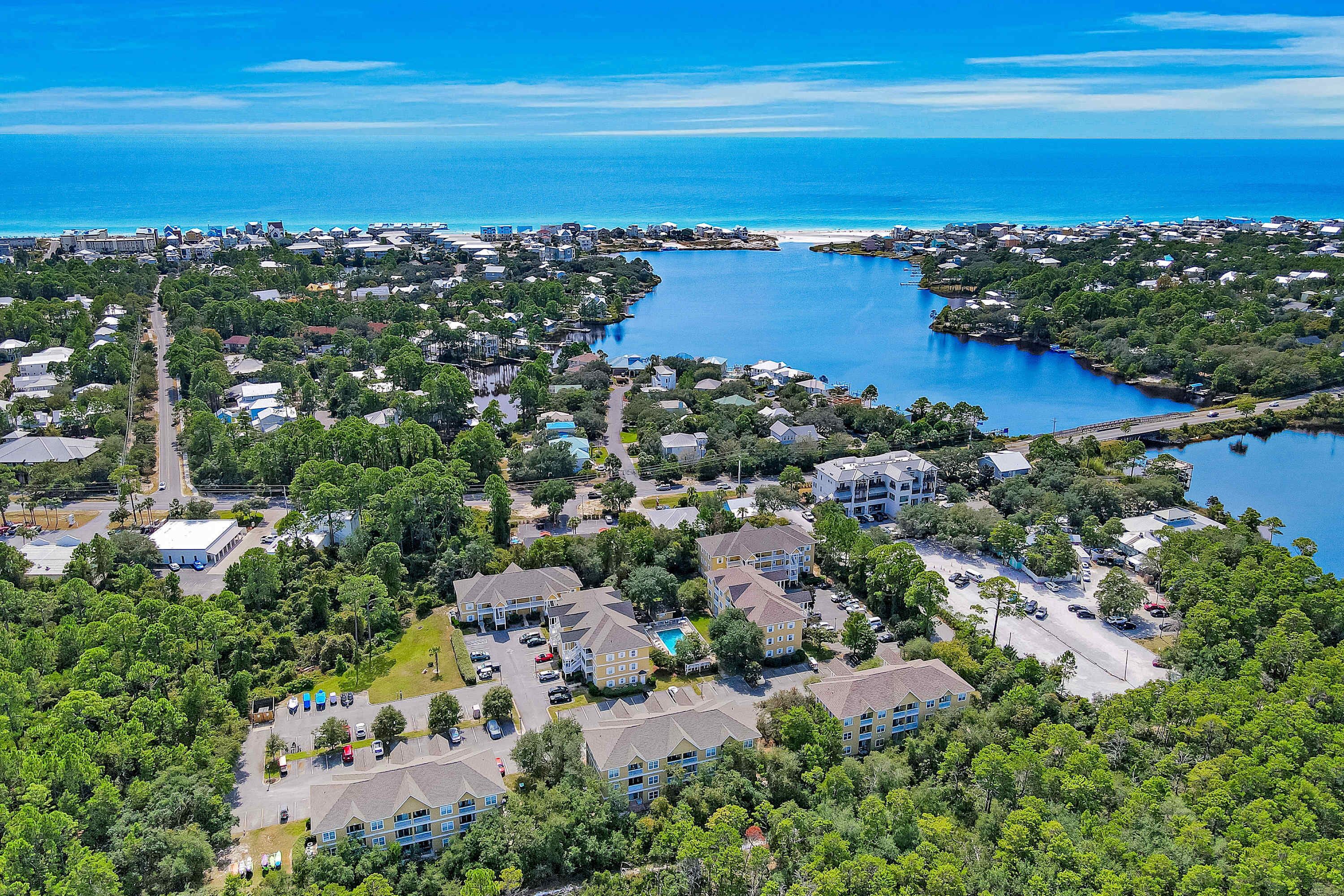 An aerial view of a coastal residential area with houses, a marina, and a large body of water.