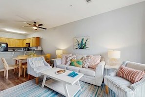 A modern living room with a sofa, coffee table, and dining area. - Pool-view condo with private balcony, washer and dryer, Wifi, 2 bikes included (Santa Rosa Beach)