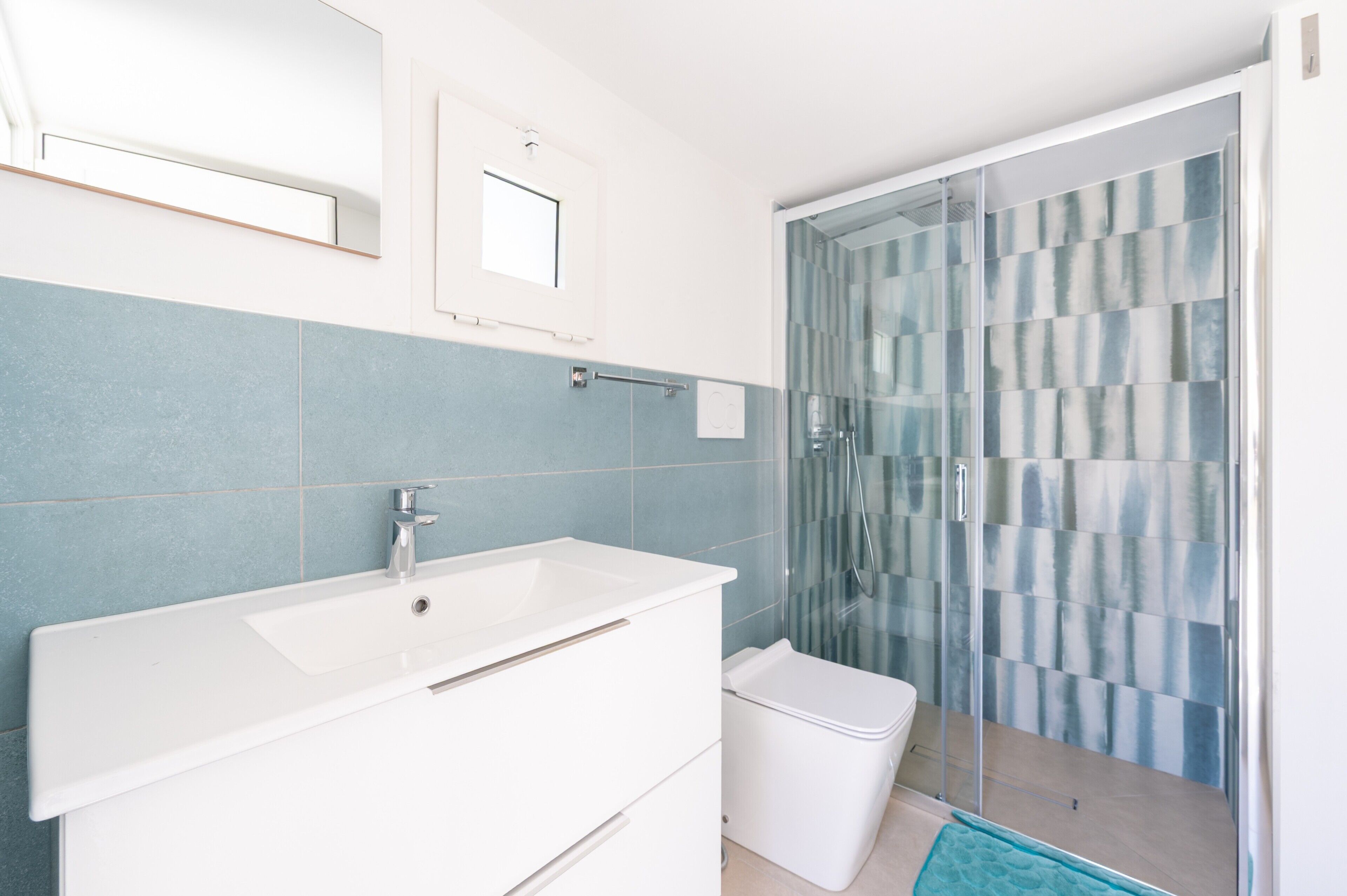 A bathroom with a white sink, a mirror, and a glass shower enclosure.