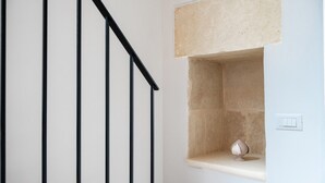 Een trap met zwarte leuningen, een beige muur en een klein plankje met een decoratief object.