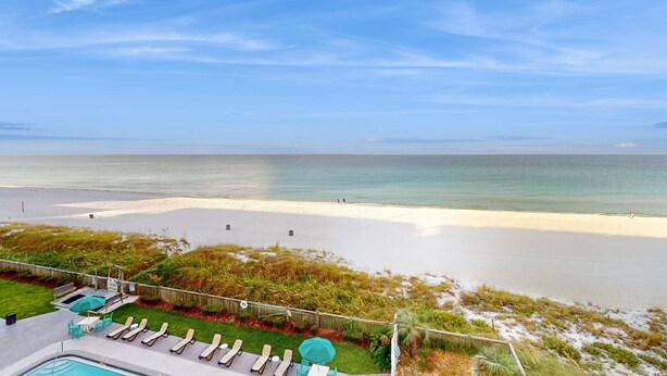 A beach view with a pool area, including lounge chairs and a small pool. - Oceanfront condo with shared pool, resort amenities, and private washer/dryer (Panama City Beach)