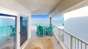 A balcony with a table and chairs, a view of the sea, and a glass door leading to an outdoor area. - Oceanfront condo with shared pool, resort amenities, and private washer/dryer (Panama City Beach)