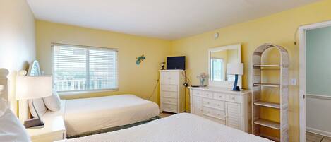 A hotel room with two beds, a dresser, a TV, and a window with blinds.