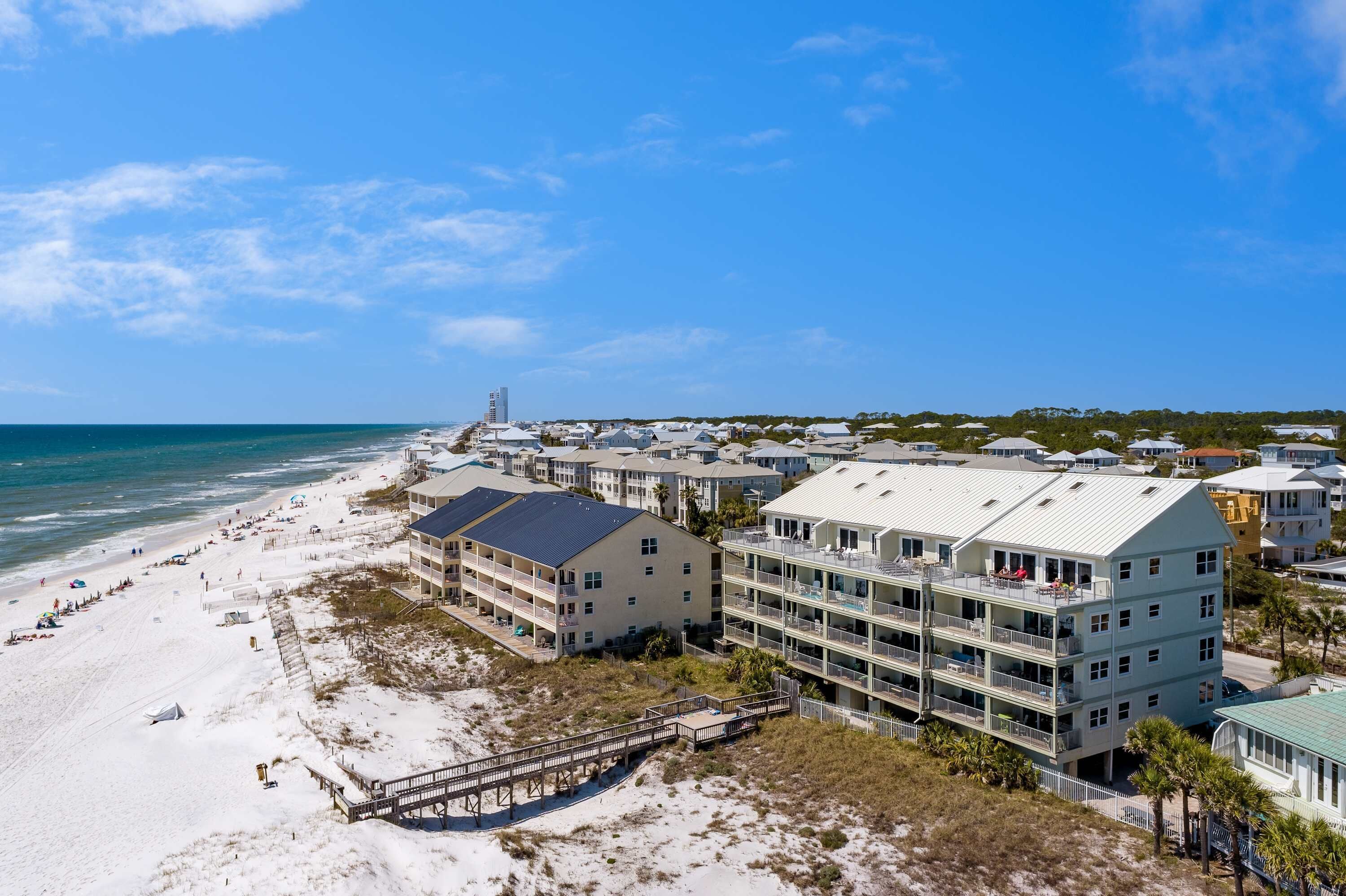 A coastal hotel with multiple floors, a beach view, and a pier.