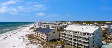 A coastal hotel with multiple floors, a beach view, and a pier.