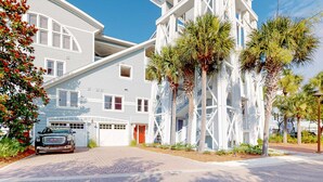 A modern building with a white exterior, a garage, and a car parked in front. - Gorgeous, updated condo with balconies, pool, & great location near 30A (Alys Beach,)
