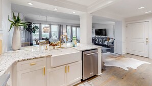 A modern kitchen with white cabinetry, a granite countertop, and a stainless steel dishwasher. - Gorgeous, updated condo with balconies, pool, & great location near 30A (Alys Beach,)