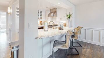 A modern kitchen with white cabinetry, a granite countertop, and a central island with bar stools.