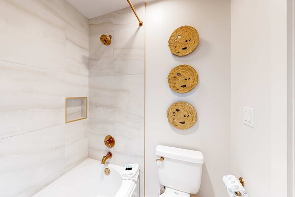 A modern bathroom with a white marble wall, a white bathtub, a toilet, and three wall-mounted circular fixtures. - Gorgeous, updated condo with balconies, pool, & great location near 30A (Alys Beach,)