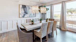 A dining area with a wooden table, wicker chairs, and potted plants. - Gorgeous, updated condo with balconies, pool, & great location near 30A (Alys Beach,)