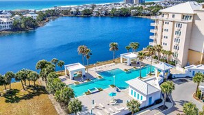 Um resort com uma piscina grande, palmeiras e vista para o oceano.