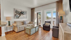 Uma sala de estar moderna com sofá, poltrona, mesa de centro e um quadro na parede.