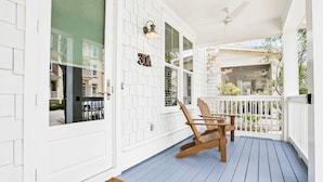 A porch with a white door, a number '30' sign, and a wooden rocking chair. - Relaxing getaway outdoor pool access, gym, bikes, central AC, & W&D (Inlet Beach)