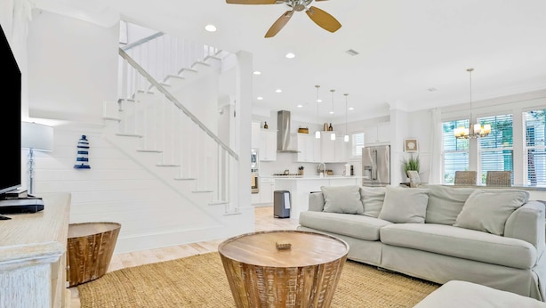 A spacious living area with a staircase, a round wooden coffee table, and a light-colored sofa. - Relaxing getaway outdoor pool access, gym, bikes, central AC, & W&D (Inlet Beach)