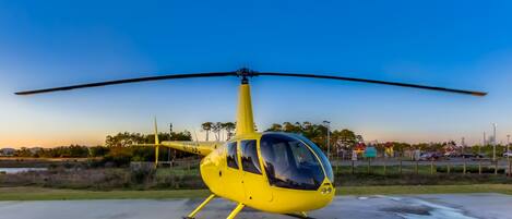 A yellow helicopter parked on a concrete surface.