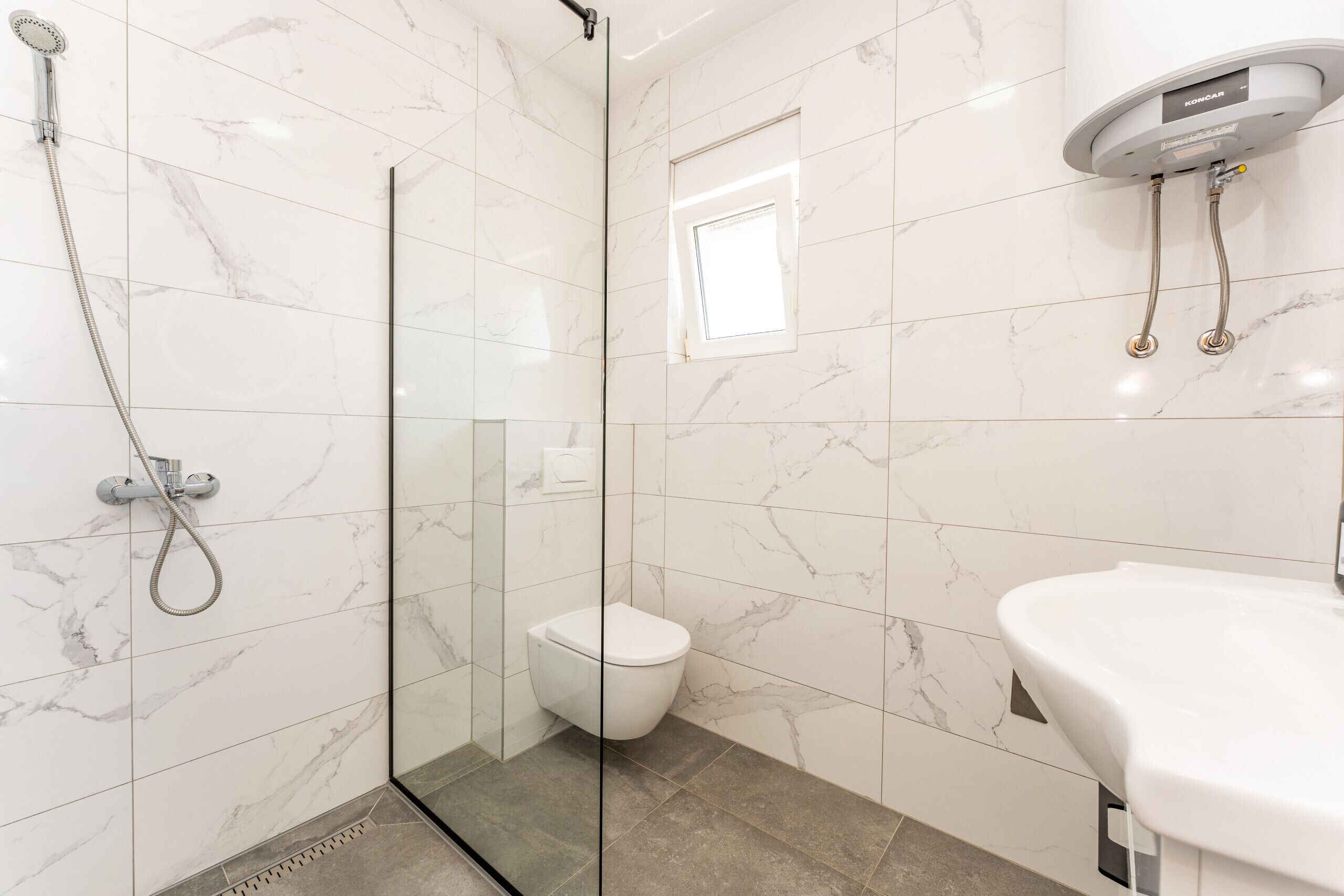 A modern bathroom with a glass shower enclosure, a toilet, and a sink.