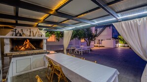 Una terrazza esterna con barbecue integrato, tavoli e sedie.