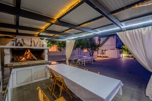 Eine Terrassenausstattung im Freien mit integriertem Grill, Tischen und Stühlen.