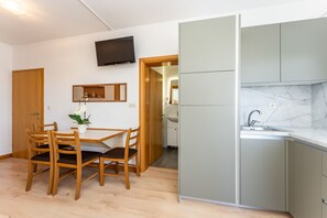 Eine moderne Küche mit grauen Schränken, einer Marmor-Spritzschutzwand und einem Holzespeisetisch mit Stühlen.