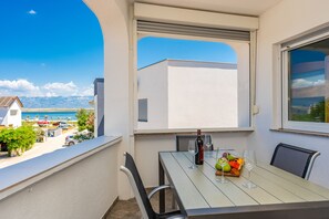 Ein Balkon mit einem Tisch für zwei Personen, einer Weinflasche und einer Obstschale.