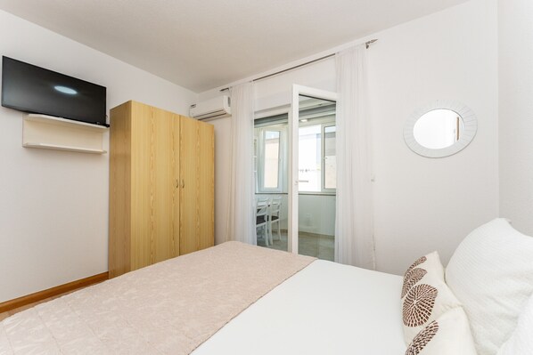 A bedroom with a bed, a wardrobe, a television, and a bathroom visible through a glass door. - Apartment Lavaran 5 (Vir)