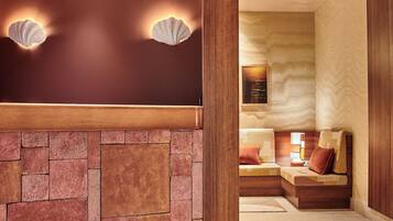 Een hotel lobby met een stenen muur, houten lambrisering en een zithoek met een bank en kussens.