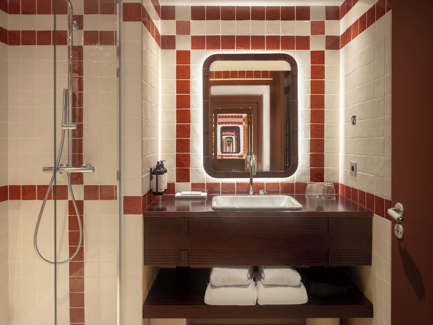 A bathroom with a shower, a sink, a mirror, and a towel rack.