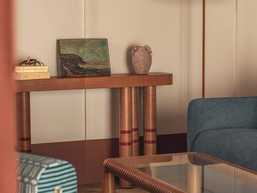 Una stanza con un divano, un tavolino da caffè, un comodino con una lampada e un quadro.