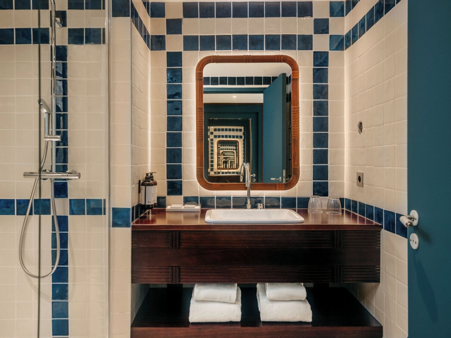 A bathroom with a shower, a sink with a mirror, and a towel rack.