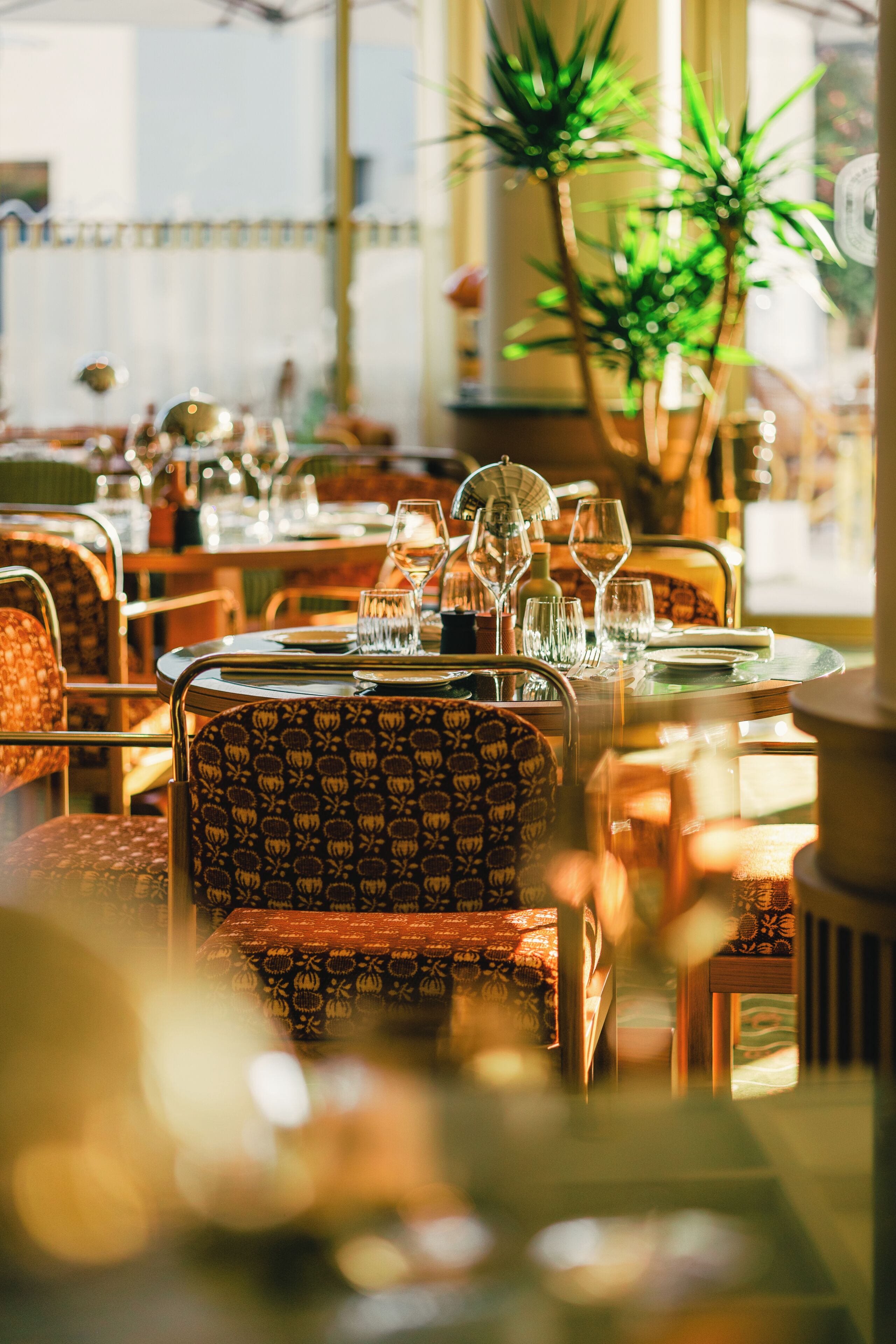 Ein Restaurantinneres mit runden Tischen, Stühlen und Gläsern.