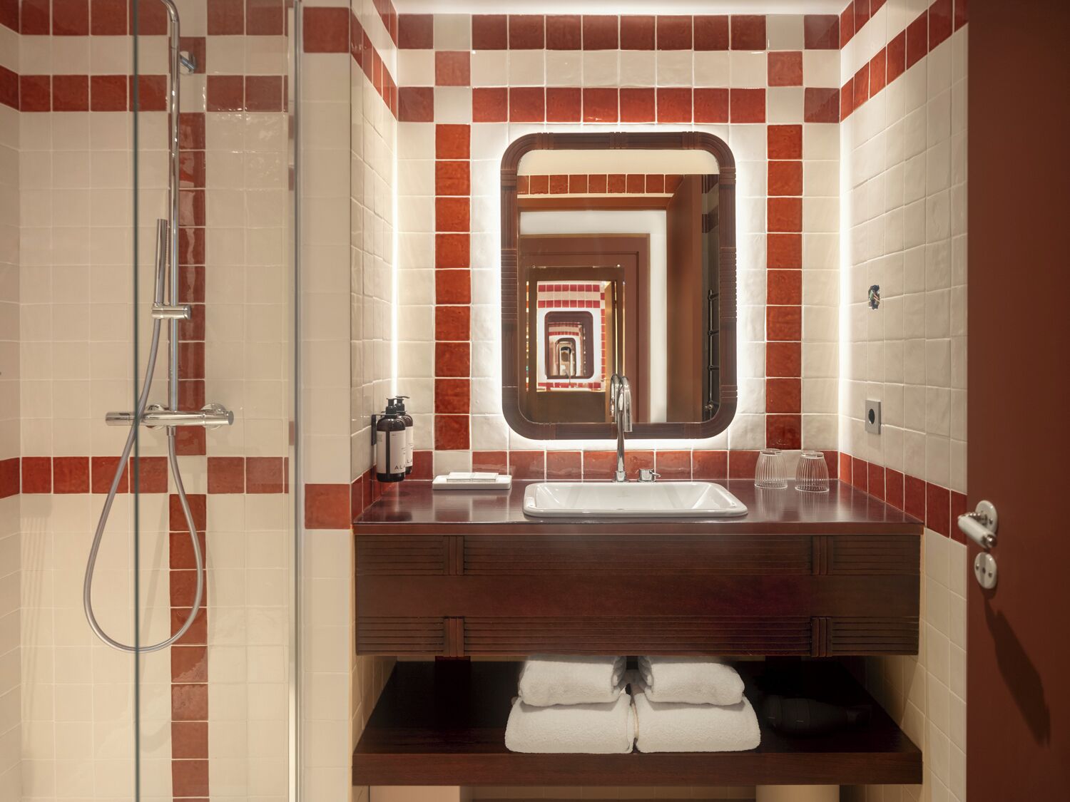 Une salle de bain équipée d’une douche, d’un lavabo, d’un miroir et d’un porte-serviettes.