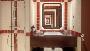 Une salle de bain équipée d’une douche, d’un lavabo, d’un miroir et d’un porte-serviettes.