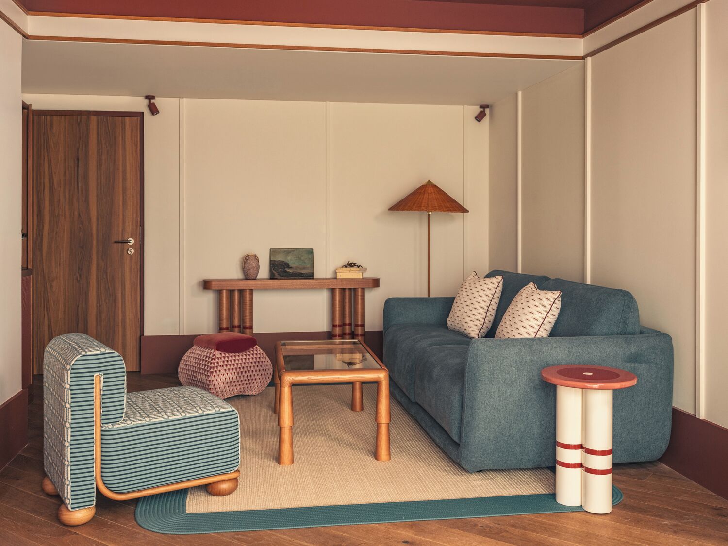 A living room with a sofa, a coffee table, a chair, a lamp, and a small table with decorative items.